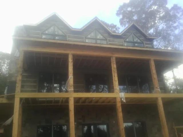 Dormers and porch framing on a large log home under construction — Roof Coating work by our crew in Cherokee